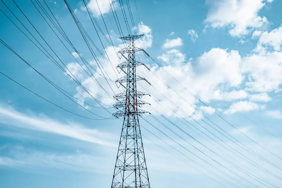 Mavi gökyüzüne karşı yüksek gerilim enerji iletim direği ve hatları